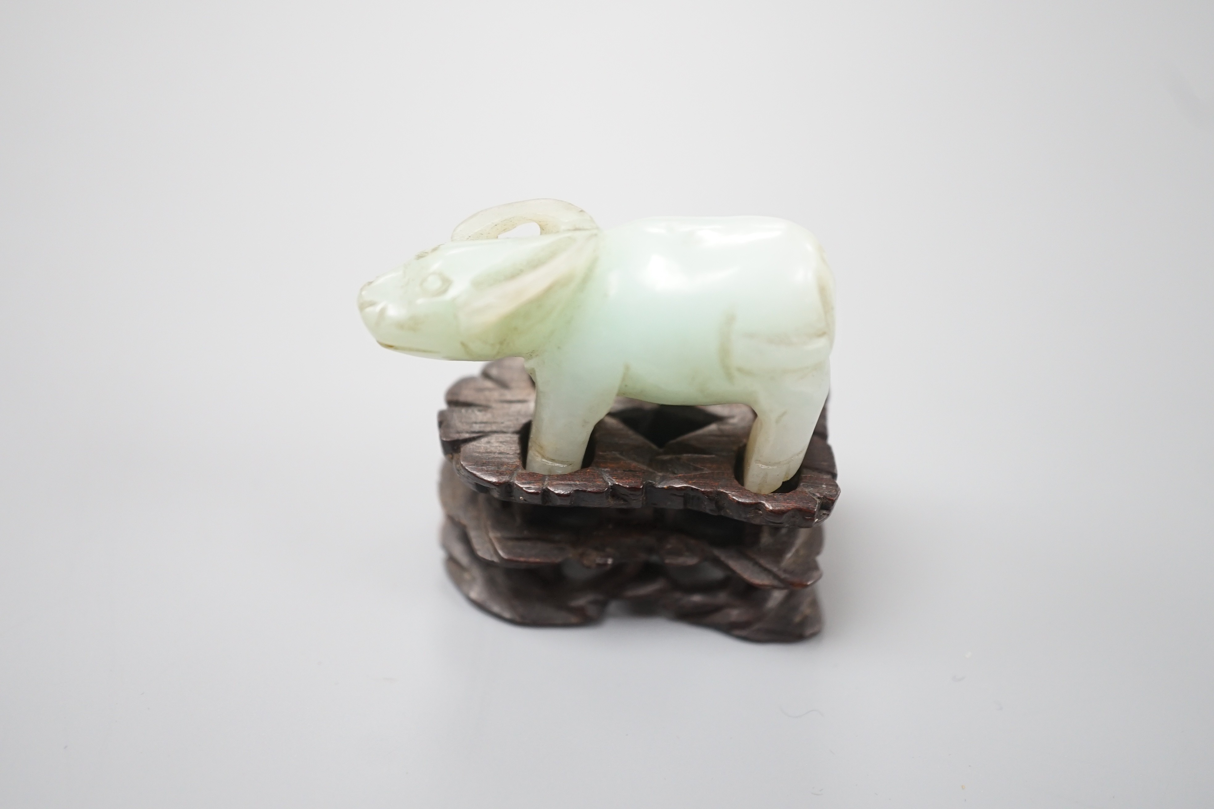 A small Chinese jade figure of a buffalo, late 19th/early 20th century, 3.8cm long, wood stand